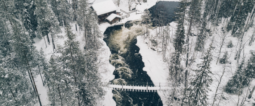 Aerial view of an icy river flowing through a winter forest