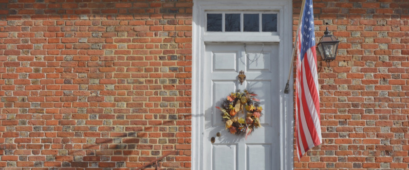An American flag hanging by a white door.