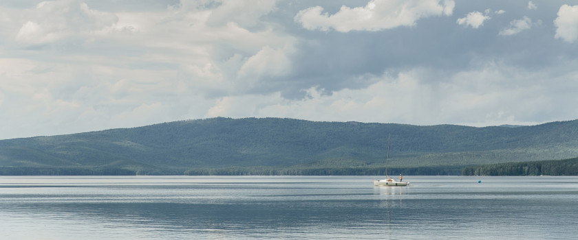 A boat floating in a lake surrounded by mountains