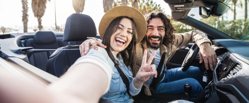 Happy couple driving convertible car in summer