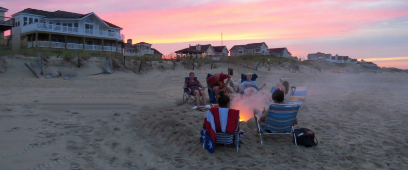 Family enjoying a bonfire on the beach at sunset