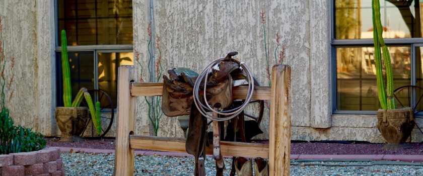 Saddle on a hitching post outside of a home.