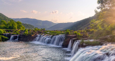 Sandstone Falls at New River Gorge National Park in West Virginia with green mountains and cascading waterfalls